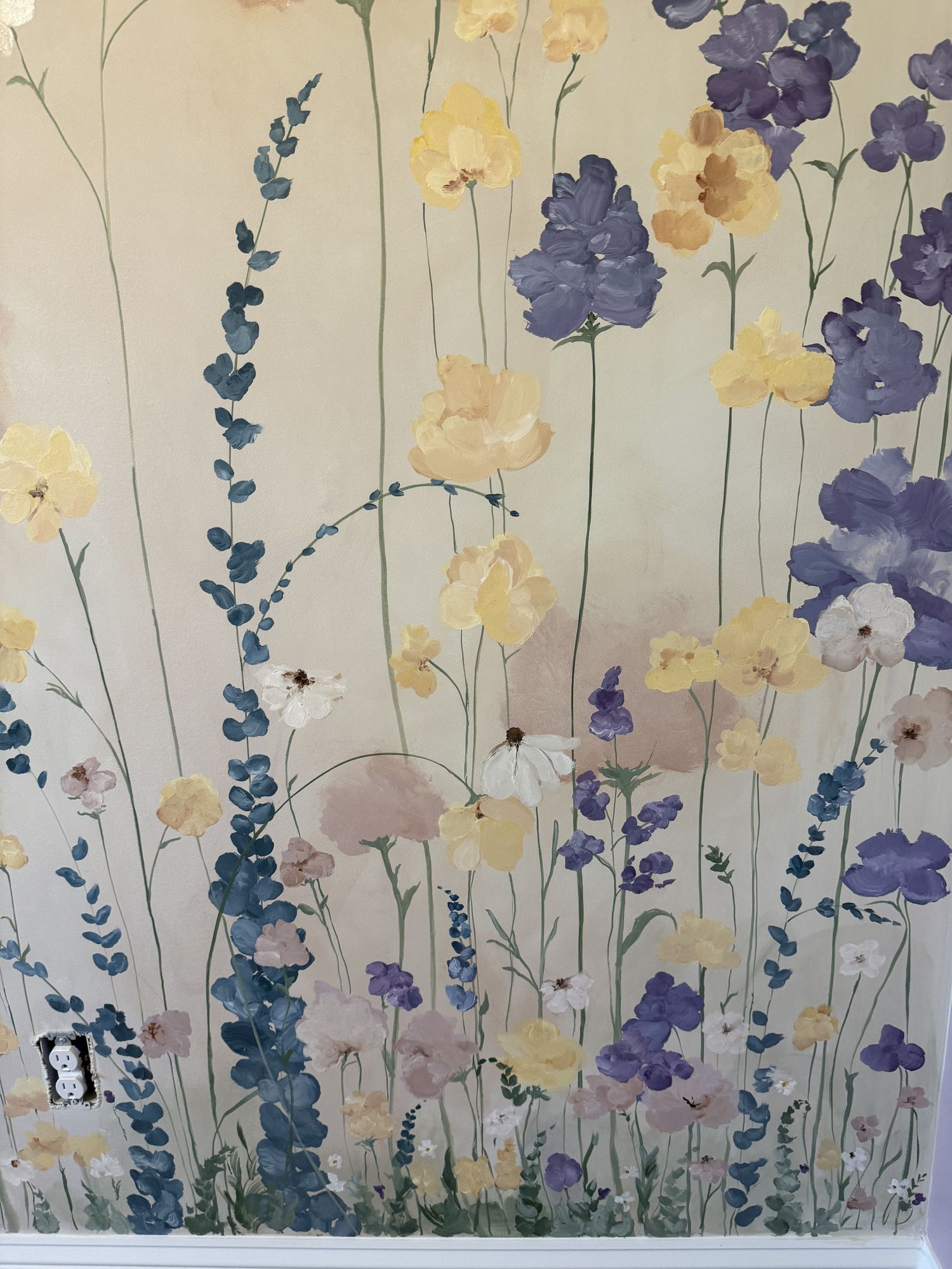Detail of hand-painted yellow and purple wildflowers against a pale wall