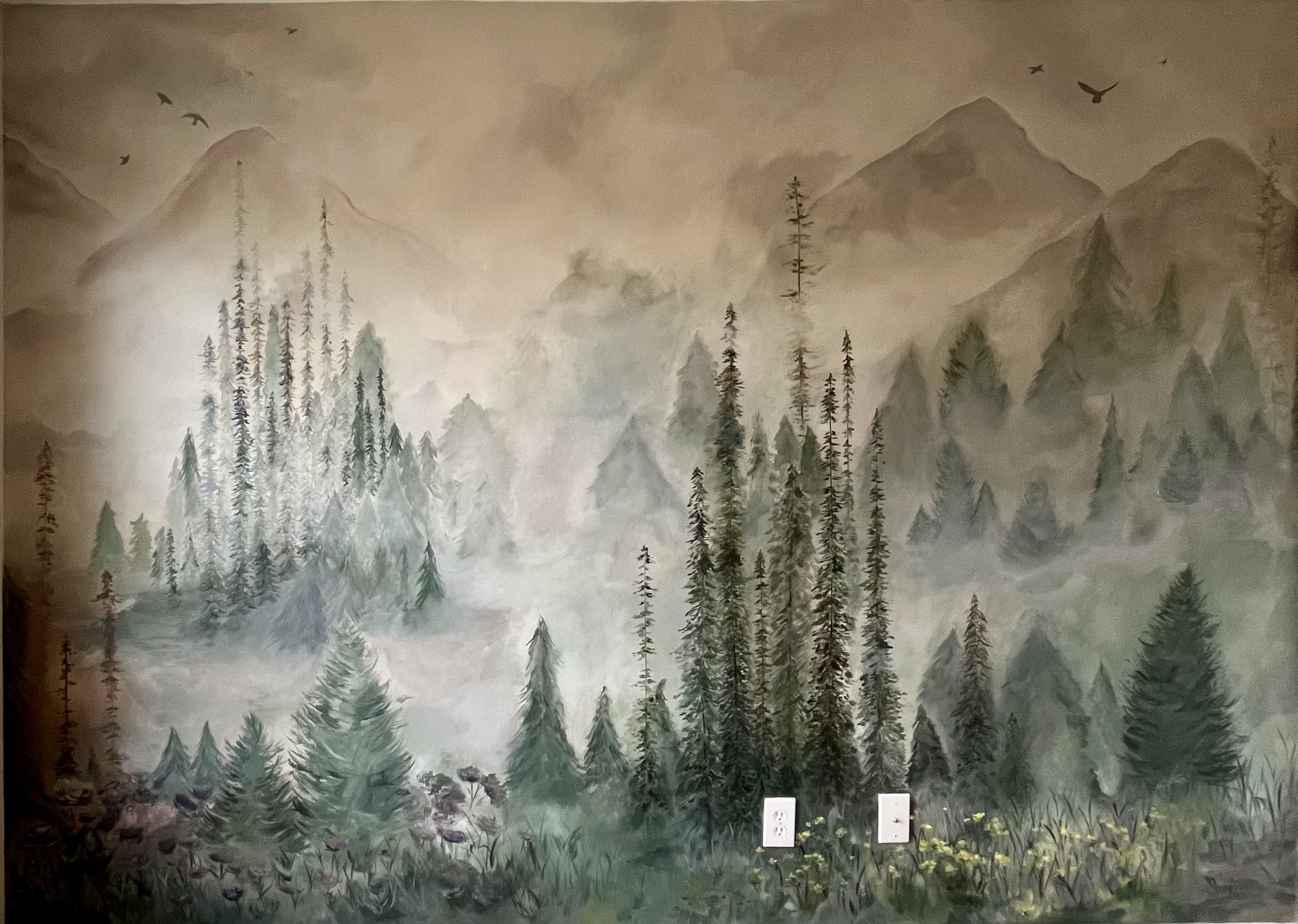 Hand-painted misty mountain forest mural covering a bedroom wall, layered pines and fog in soft greens and greys