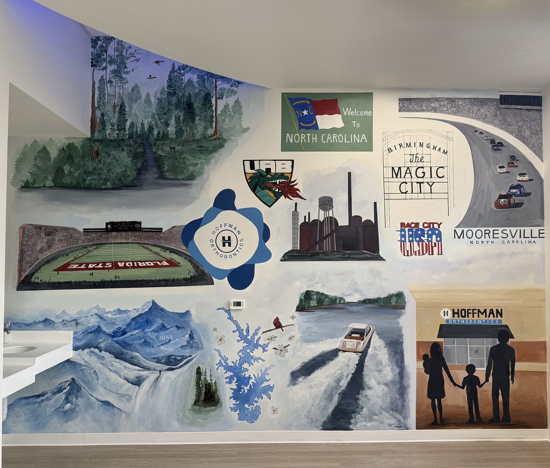 Custom story mural for a dental practice in Mooresville, NC: North Carolina flag, Birmingham Magic City sign, university crests, a lake and mountains, and a family silhouette
